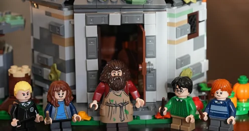 Lego-figuren van personages uit Harry Potter staan voor een gedetailleerd Lego-model van een huisje.