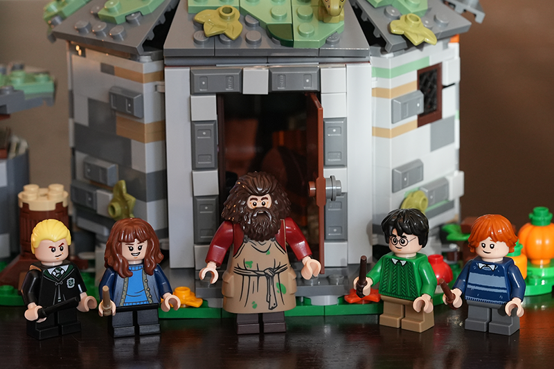 Lego-figuren van personages uit Harry Potter staan voor een gedetailleerd Lego-model van een huisje.