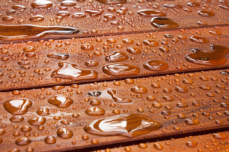 Waterdruppels op geïmpregneerd houten oppervlak, dat waterafstotend is gemaakt.